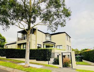 a house with a tree in front of it at Three Monkeys Residence in Kellyville