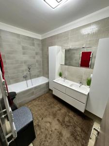 y baño con 2 lavabos, bañera y espejo. en VRG 1 Exkluzív Apartman en Debrecen