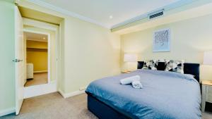 a bedroom with a blue bed with two towels on it at Three Monkeys Residence in Kellyville