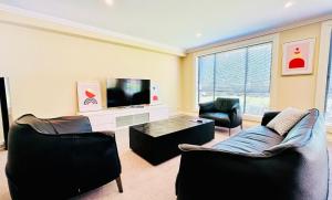 a living room with two chairs and a flat screen tv at Three Monkeys Residence in Kellyville