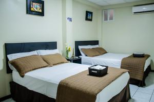 a hotel room with two beds and two chairs at Hotel Paris in Machala