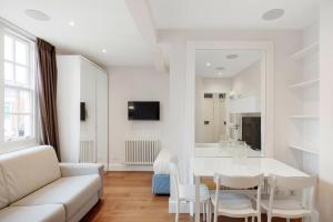 Biały salon z białą kanapą i stołem w obiekcie Beaufort Gem Chelsea Apartment w Londynie