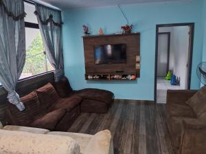 ein Wohnzimmer mit einem Sofa und einem Flachbild-TV in der Unterkunft Iguaçu House in Foz do Iguaçu