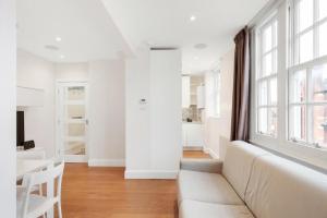 Biały salon z kanapą i oknem w obiekcie Beaufort Gem Chelsea Apartment w Londynie