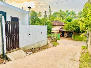 an empty street in front of a house with a fence at Ru Retreat Weligama in Weligama