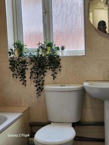 uma casa de banho com um WC, um lavatório e uma janela em Cozy 2 bed Flat/Apt in East London- Nice Estate. em Goodmayes