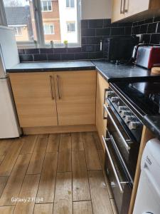 a kitchen with a stove and a wooden floor at Cozy 2 bed Flat/Apt in East London- Nice Estate. in Goodmayes