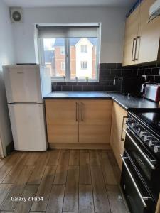 uma cozinha com um frigorífico branco e uma janela em Cozy 2 bed Flat/Apt in East London- Nice Estate. em Goodmayes