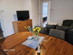 uma sala de estar com uma mesa de madeira com flores em Cozy 2 bed Flat/Apt in East London- Nice Estate. em Goodmayes