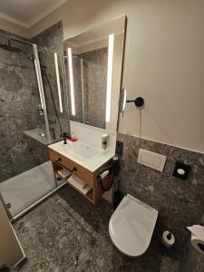 uma casa de banho com um lavatório, um WC e um espelho. em Hotel Gasthof Stieglers 