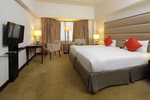 a hotel room with a large bed and a television at Aryaduta Pekanbaru in Pekanbaru