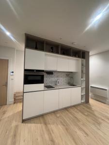 uma cozinha com armários brancos e piso em madeira em London Heathrow Airport Apartment Voyager House Terminal 12345 - EV electric and Parking available em New Bedfont