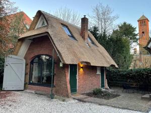 ein kleines Backsteinhaus mit einem Strohdach in der Unterkunft Cottage Guest House in Wassenaar in Wassenaar