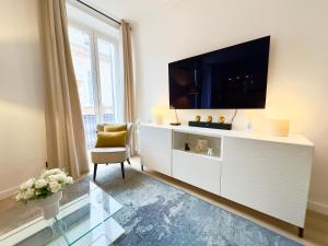 a living room with a tv on a white cabinet at Luxueux 3 pièces 80m2 - Espace bureau -1mn Beach Croisette in Cannes