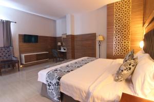 a hotel room with a bed and a television at Grand Amira Hotel in Solo