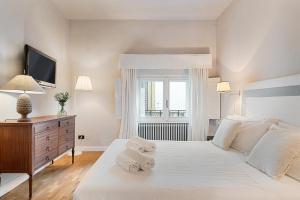 um quarto branco com uma grande cama branca e uma janela em Tornabuoni Living - Luxury Apartments Collection em Florença