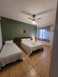 a bedroom with two beds and a green wall at Hotel Aurora in Olímpia