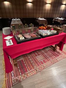 a table with a pink table cloth with food on it at Hotel du Pot d'Etain in Châlons-en-Champagne