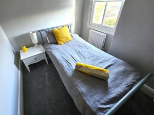 a bedroom with a bed with a yellow pillow and a window at Knighton Villa in Leicester