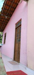 um edifício cor-de-rosa com uma porta de madeira em Casa 2/4 em Itacimirim - Beira do Rio Pojuca em Camaçari