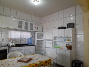 a small white kitchen with a table and a refrigerator at Casa em Cabo Frio in Cabo Frio