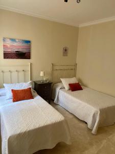 1 dormitorio con 2 camas, mesa y una pintura en SUEÑOS DEL MAR, en Motril