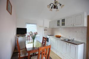 una cocina con mesa y sillas y una cocina con armarios blancos. en Apartment Jure, en Trogir