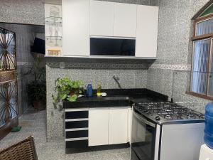 a kitchen with white cabinets and a stove at Casa Geminada in Contagem