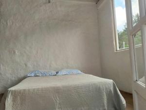 uma cama num quarto branco com uma janela em El chalet de Agnes em Villa de Leyva
