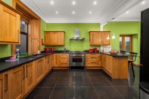 uma cozinha com armários de madeira e paredes verdes em Fontain House: 4 bedroom Victorian villa em Blairgowrie