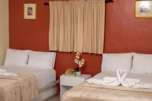 duas camas num quarto com paredes vermelhas em Diosamar Hotel y Suites em Santo Domingo