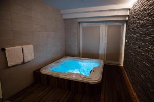 a bathroom with a tub with blue water in it at GOSTILNA S PRENOČIŠČI PAV in Rakek