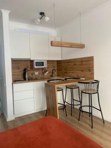 una cocina con armarios blancos y una mesa con taburetes en Апартаменты Promenade Burabay, en Burabay