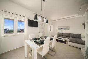a white dining room with a white table and chairs at Villa Pearl in Tribunj