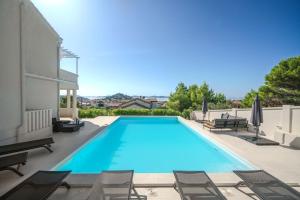 a swimming pool with chairs and umbrellas next to a house at Villa Pearl in Tribunj