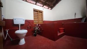 a red bathroom with a toilet and a sink at The Wind Chime - SUPRAD Estate in Suntikoppa
