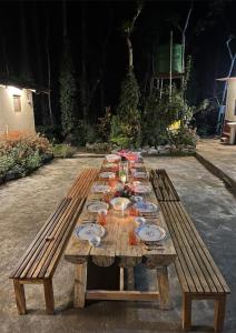 a long wooden table with plates and wine glasses at The Wind Chime - SUPRAD Estate in Suntikoppa