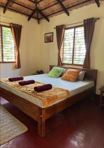 a large bed in a room with windows at The Wind Chime - SUPRAD Estate in Suntikoppa