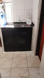 a kitchen with a black sink and a tile floor at Casa e camping Reinaldo e Julia recanto das árvores in Itamonte