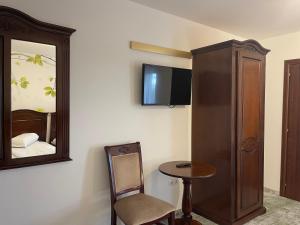 een kamer met een spiegel, een stoel en een tafel bij Pensiune Premier in Doctor Petru Groza