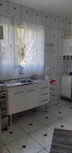 a white kitchen with a sink and a window at Sitio Terra Azul in Guarulhos