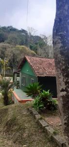 uma pequena casa verde com um alpendre em frente em Sitio Terra Azul em Guarulhos