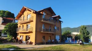 Un bâtiment jaune avec des personnes assises à l'extérieur dans l'établissement Apartmani Šćit, 