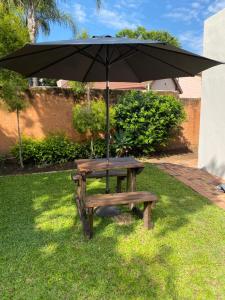 ein Picknicktisch und ein Regenschirm im Gras in der Unterkunft De Vlei, Pretoria East in Pretoria