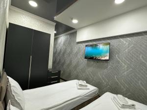 a bedroom with two beds and a tv on the wall at VIP Hotel in Tashkent