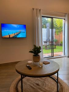 a living room with a table and a tv on the wall at De Vlei, Pretoria East in Pretoria