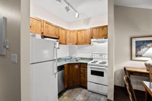 a kitchen with white appliances and wooden cabinets at Cahilty #417 home in Sun Peaks