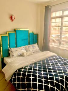 1 dormitorio con 1 cama con cabecero azul y ventana en VICTOR'S SERENE STAYS, en Nairobi