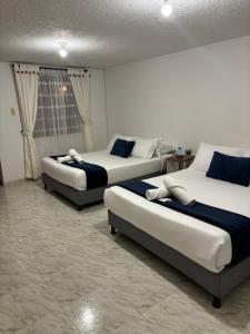 um quarto com três camas num quarto em Merak Hostel em Villa de Leyva