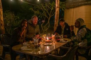 een groep mensen die rond een tafel zitten met eten bij Sunsetview Bardia in Bardiyā